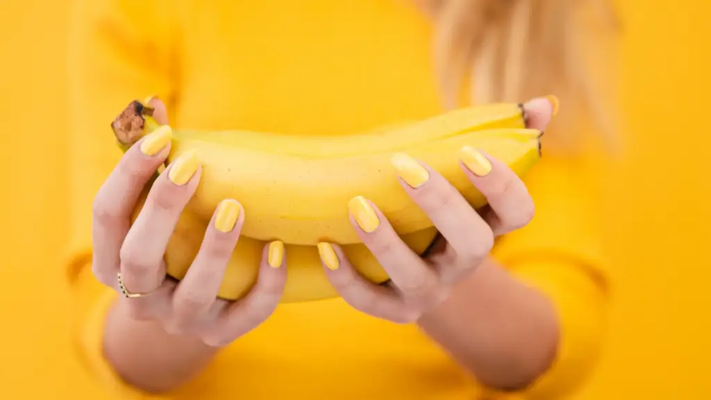Close-up of a woman holding bananas with vibrant nails