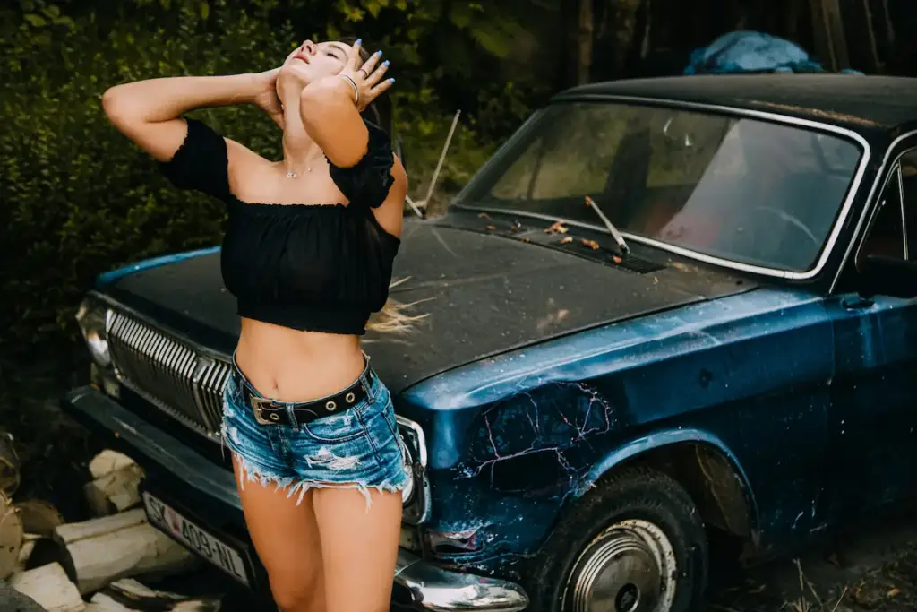Confident woman posing in front of a vintage car
