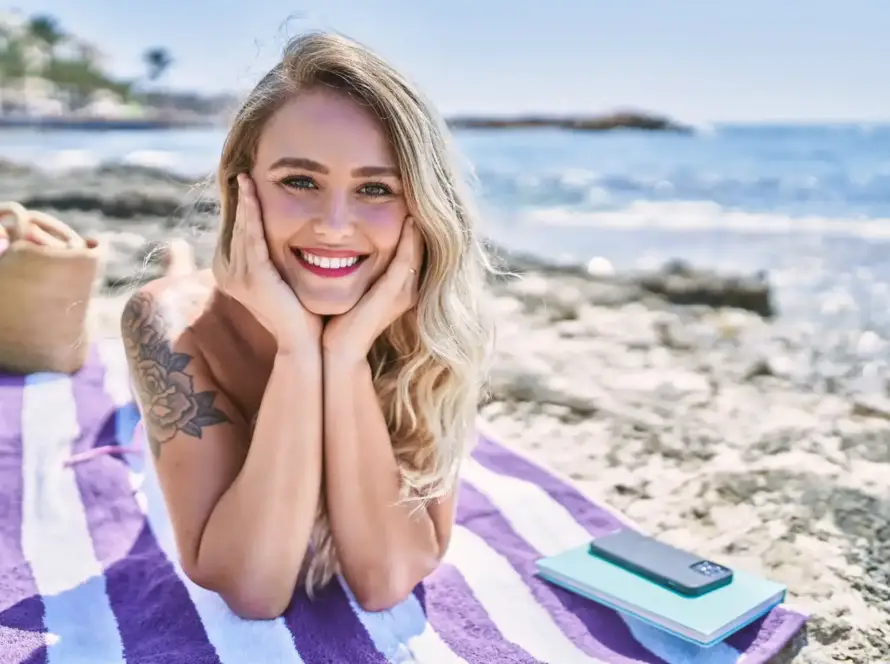 Cheerful blonde woman relaxing on a beach towel, illustrating lifestyle appeal for sell rabbit vibrator on eBay Australia.