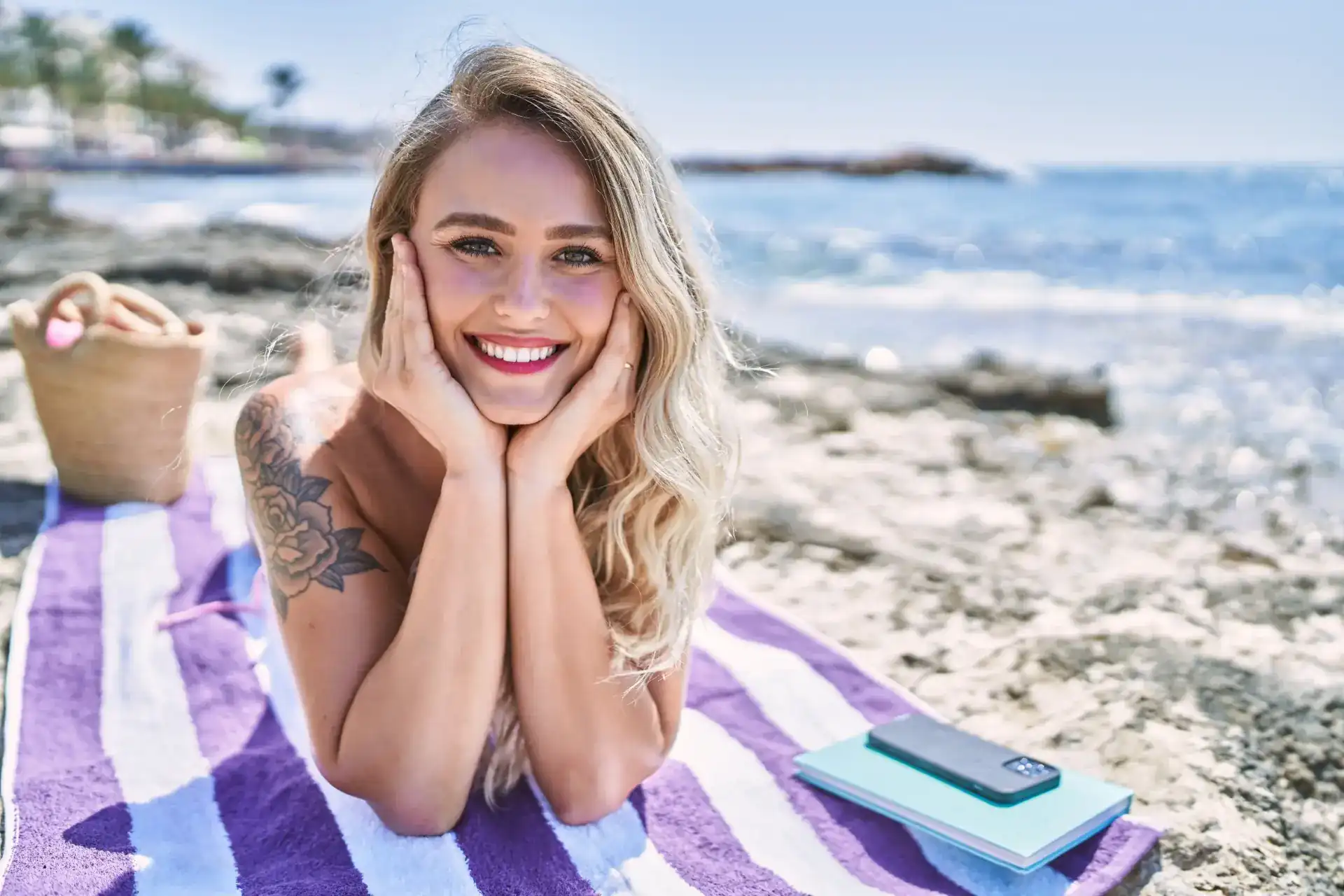 Cheerful blonde woman relaxing on a beach towel, illustrating lifestyle appeal for sell rabbit vibrator on eBay Australia.