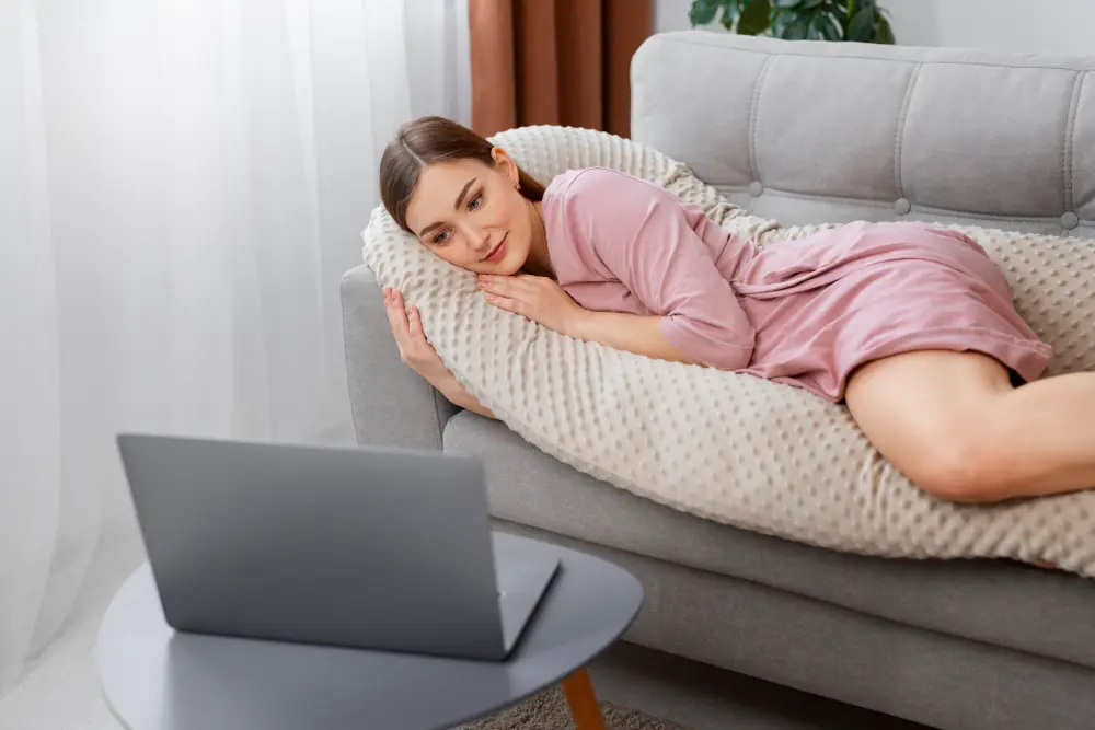 Happy woman lounging on a sofa with a laptop.