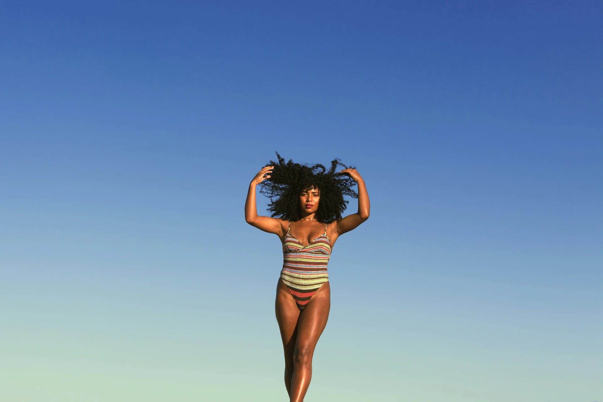 Confident woman standing under the blue sky, symbolizing empowerment and self-care. Explore Gaia in Love’s ladies sexy toy designed for pleasure and safety.