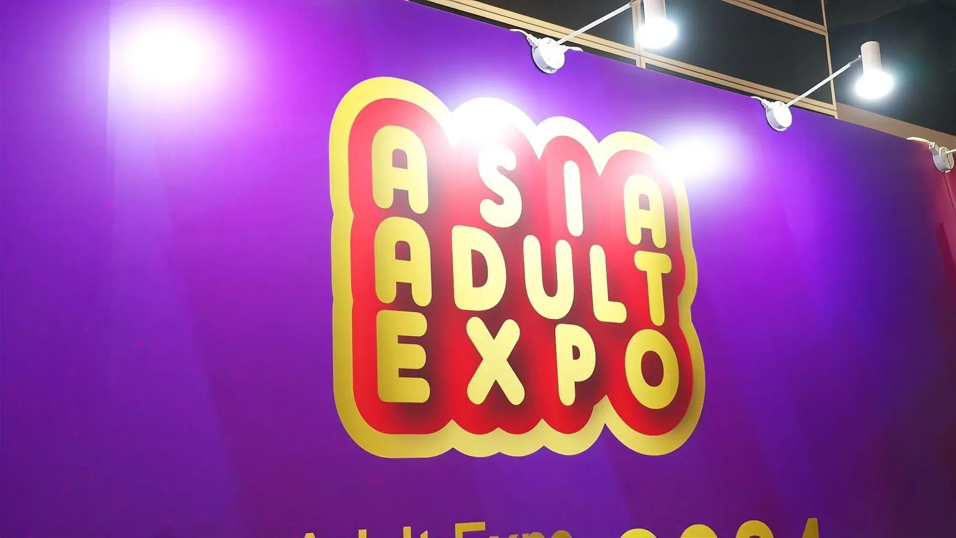 Asia Adult Expo official signage with vibrant purple and gold branding, highlighting the premier B2B adult industry trade show. Gaia in Love participates in the event.