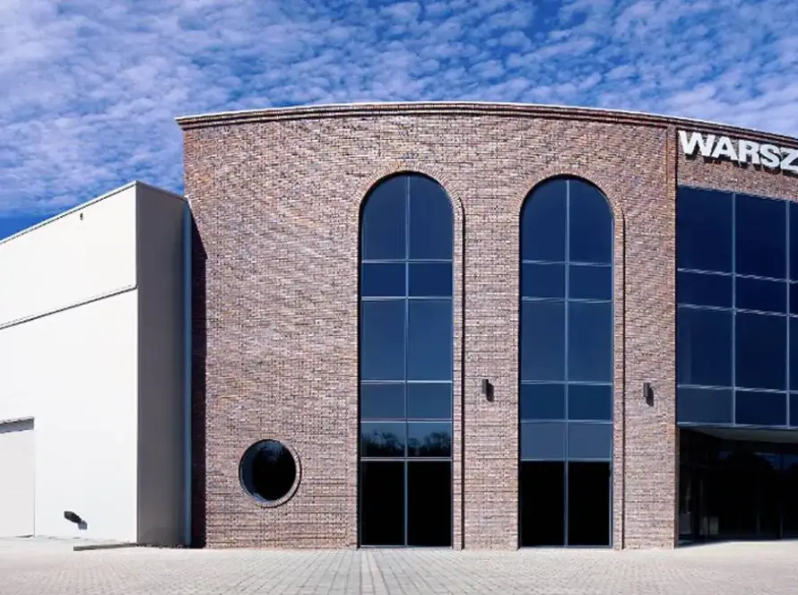 A modern brick-and-glass exhibition center under a clear blue sky, serving as the official venue for EroChain Expo 2025.