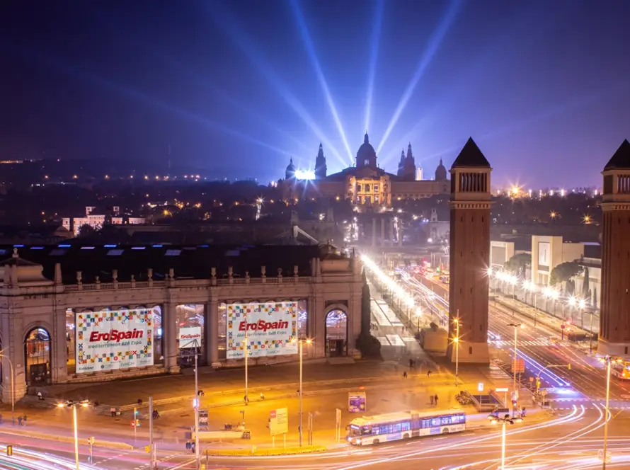 A stunning night view of Fira de Barcelona, the venue for EroSpain 2025 Barcelona. The illuminated exhibition hall showcases banners of the Mediterranean B2B Expo, highlighting its global influence. Gaia in Love connects with industry leaders at this prestigious event.