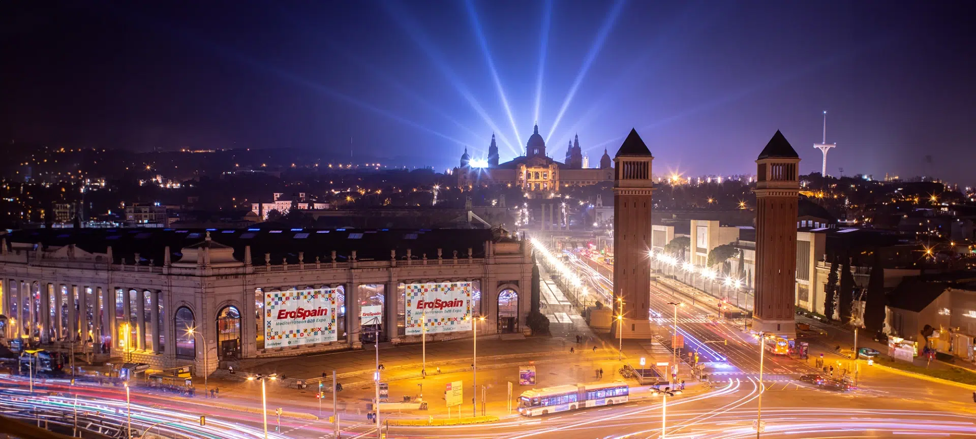 A stunning night view of Fira de Barcelona, the venue for EroSpain 2025 Barcelona. The illuminated exhibition hall showcases banners of the Mediterranean B2B Expo, highlighting its global influence. Gaia in Love connects with industry leaders at this prestigious event.