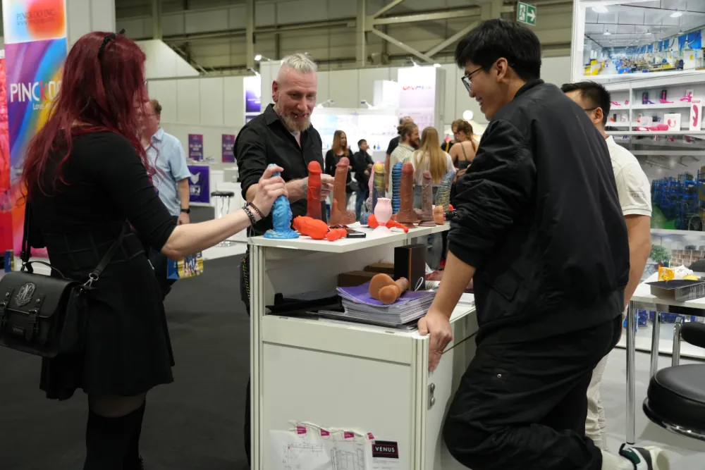 Attendees discovering a variety of adult toys and novelties at a bustling booth in VENUS Berlin 2025.