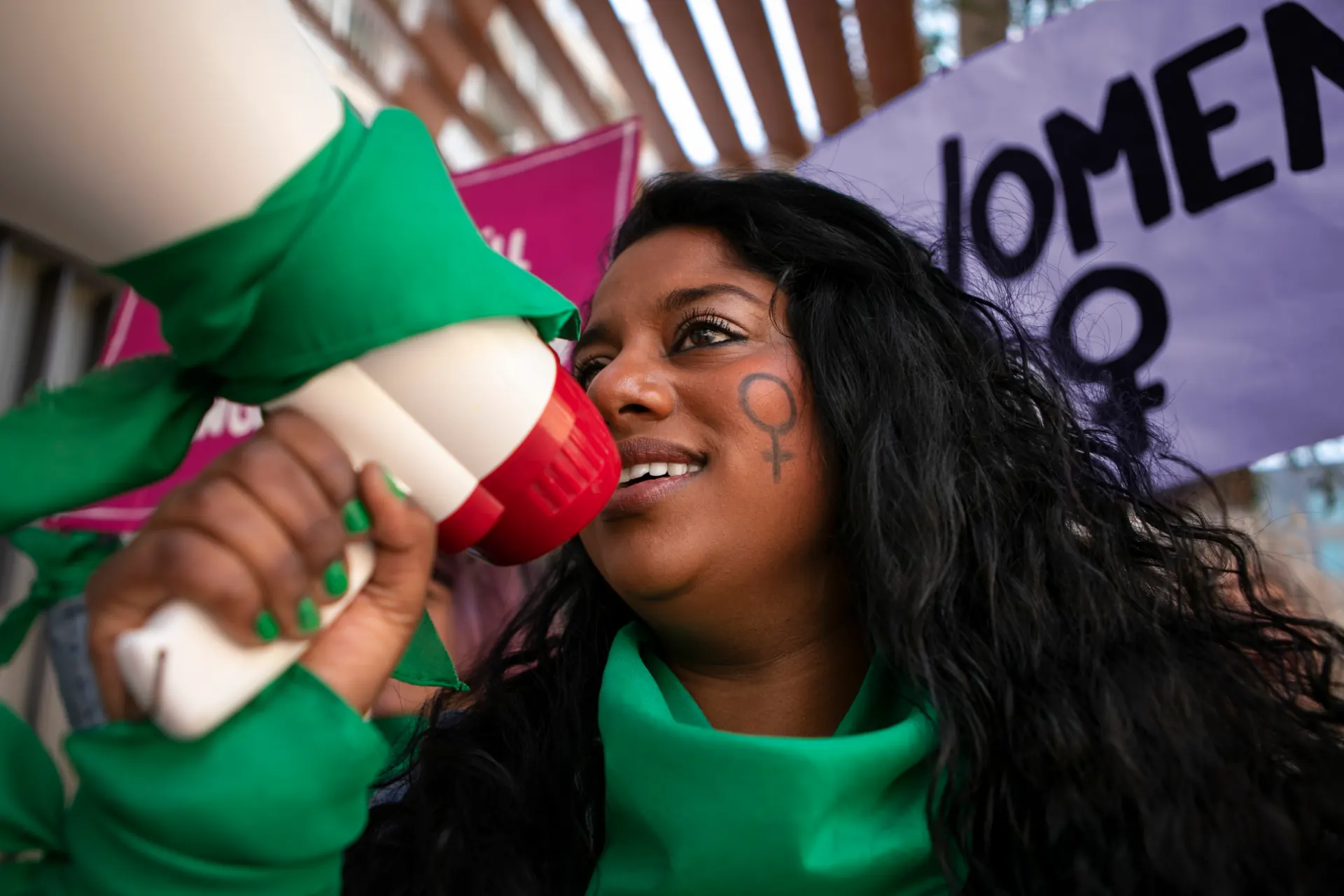 A passionate woman advocating for women's rights, speaking through a megaphone at a protest. Gaia in Love supports female empowerment and open discussions on Nigerian porn websites and sexual wellness.