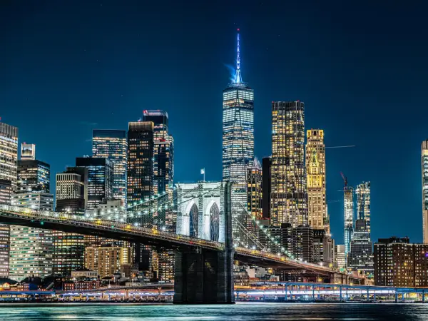 Night view of New York City skyline with Brooklyn Bridge, symbolizing global connection, innovation, and trust – Gaia Sex Tech