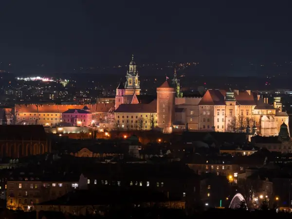 Nocny widok na zamek królewski na Wawelu w Krakowie, pięknie oświetlony na tle miasta.