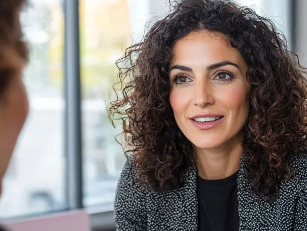 Donna italiana con sorriso cordiale in un incontro professionale, simbolo di comunicazione e fiducia.