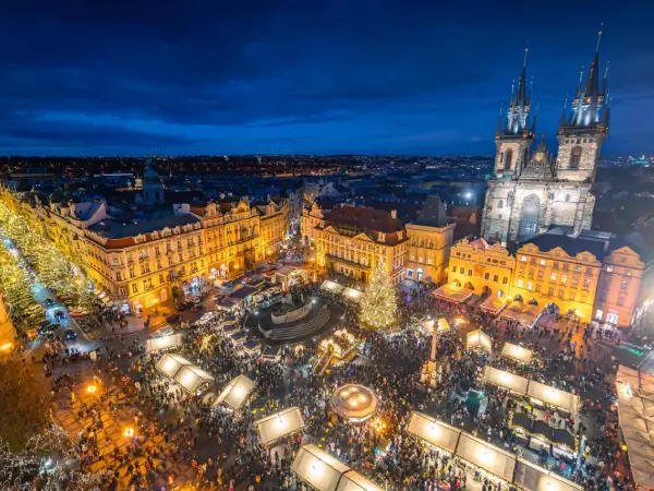 Noční pohled na Staroměstské náměstí v Praze s vánočním trhem a osvětleným kostelem Matky Boží před Týnem.