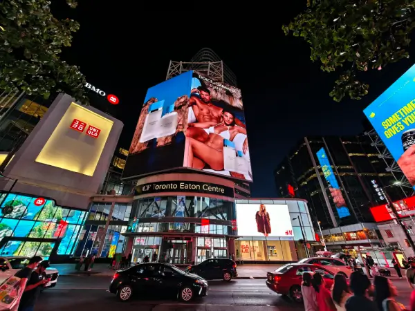 Night view of downtown Toronto with illuminated billboards and storefronts at the Eaton Centre, showing a vibrant urban business environment.