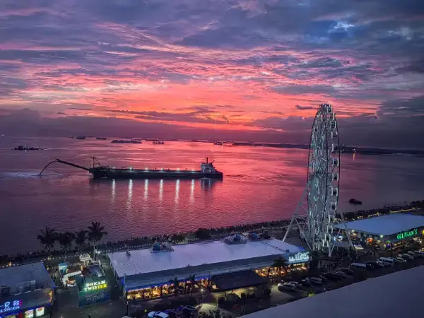 Sunset view over Manila Bay with the MOA ferris wheel and waterfront shops, capturing the vibrant evening skyline of the Philippines.
