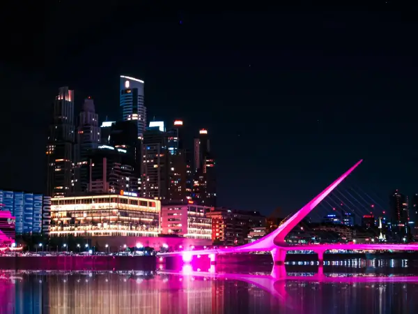 Vista nocturna de Puerto Madero con el Puente de la Mujer iluminado en tonos rosados.