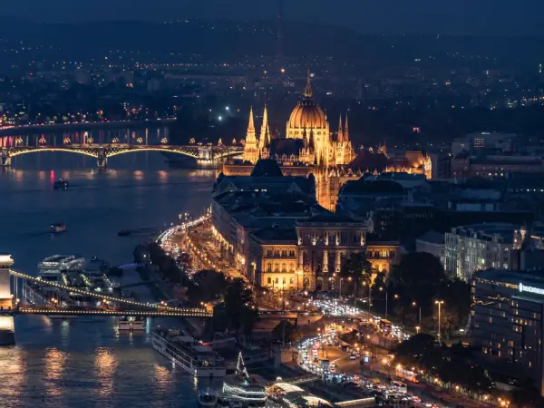 Budapest éjszakai látképe a Parlament épületével és a kivilágított Duna-parttal, lenyűgöző és elegáns hangulatban.