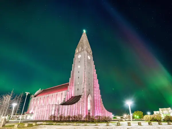 Hallgrímskirkja í Reykjavík upplýst í bleikum litum undir norðurljósum, tákn um fegurð og nýsköpun á Íslandi.