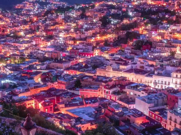 Vista panorámica nocturna de Guanajuato iluminada con luces coloridas, mostrando la belleza urbana de México.