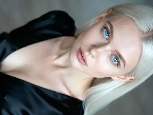 Sinisilmne blond naine mustas kleidis vaatab enesekindlalt kaamerasse.