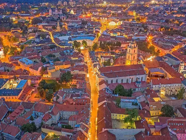 Vilniaus senamiesčio panorama sutemus, apšviestos gatvės ir raudoni stogai iš paukščio skrydžio.