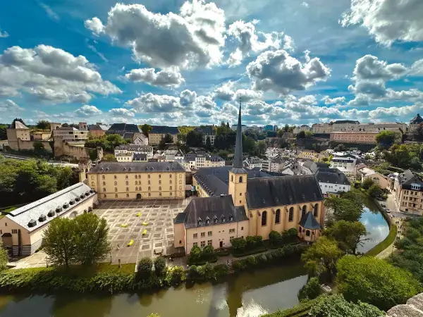 Vue panoramique du vieux quartier de Luxembourg avec église, bâtiments historiques et rivière sous un ciel nuageux, visuel d’ambiance pour Gaia Sex Tech Luxembourg.