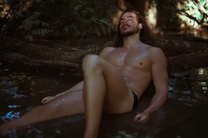 Sensual male model in a forest stream, representing Gaia in Love masturbation cups for men.