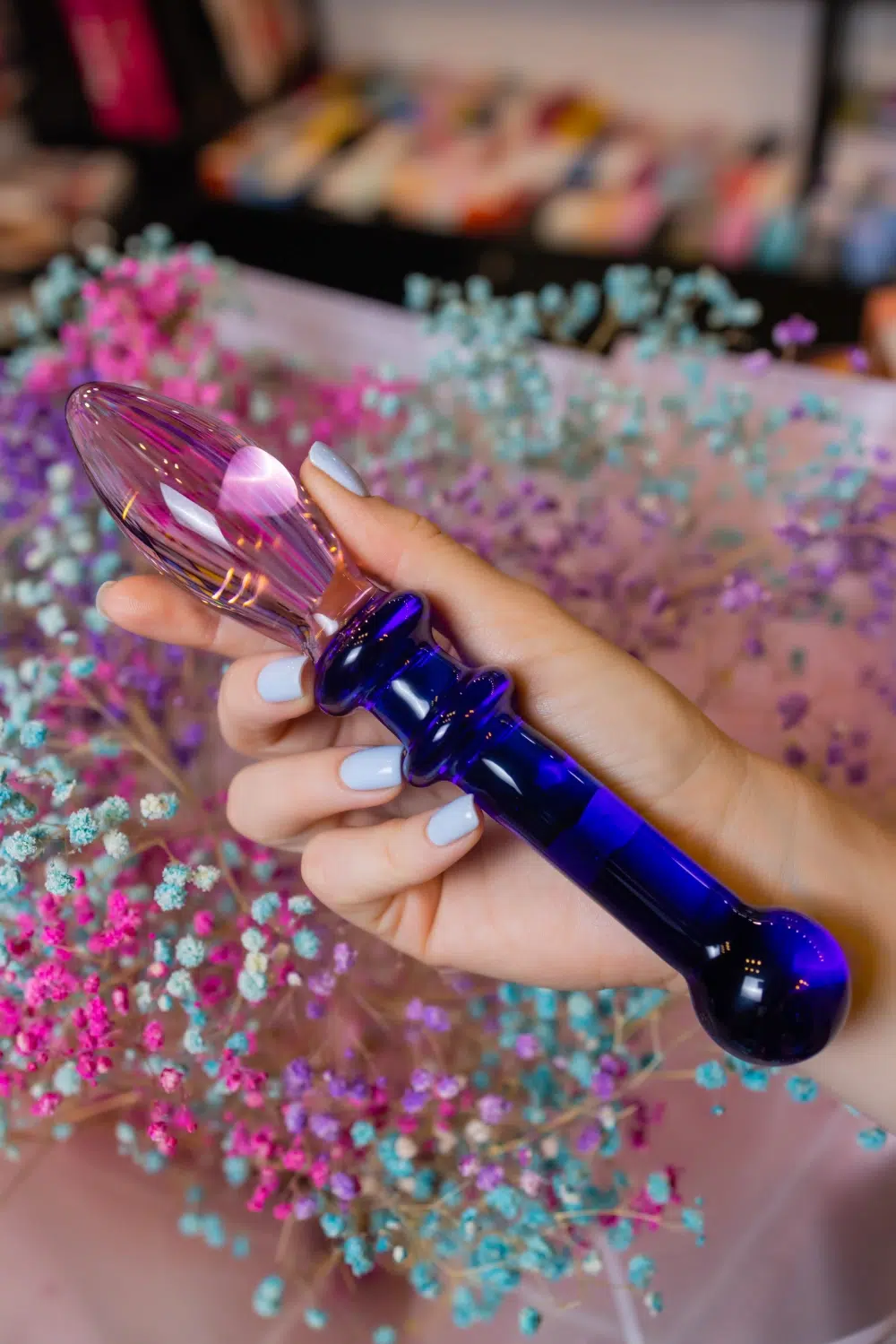 Glass anal plug with blue faceted base held in hand, close-up
