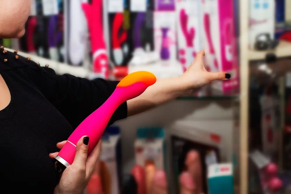 Person holding a pink sex toy in a store setting, representing B2B online selling to adult retailers and distributors