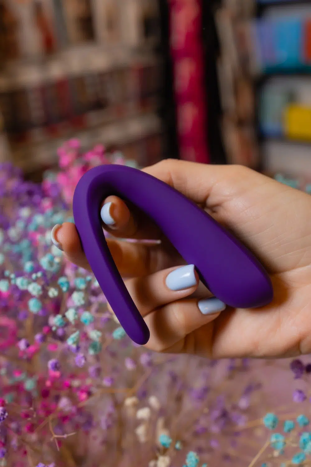 Hand holding a purple U-shaped vibrator with a soft silicone finish