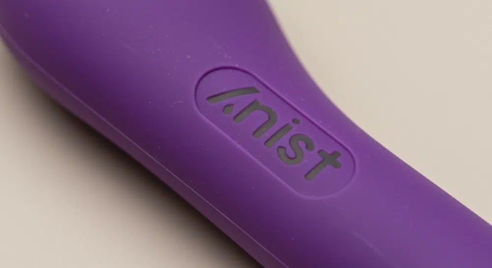 Close-up of a purple silicone vibrator showing a recessed, laser-engraved “Kinist” logo on the surface.