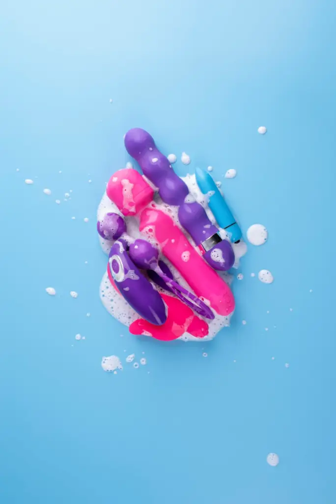 Colorful waterproof sex toys with foam on a blue background, illustrating their ability to handle water exposure in various designs.