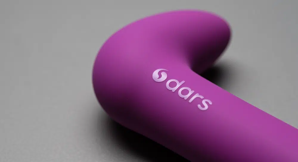 Close-up of a purple silicone vibrator with a crisp silk-screen printed “dars” logo on the handle.