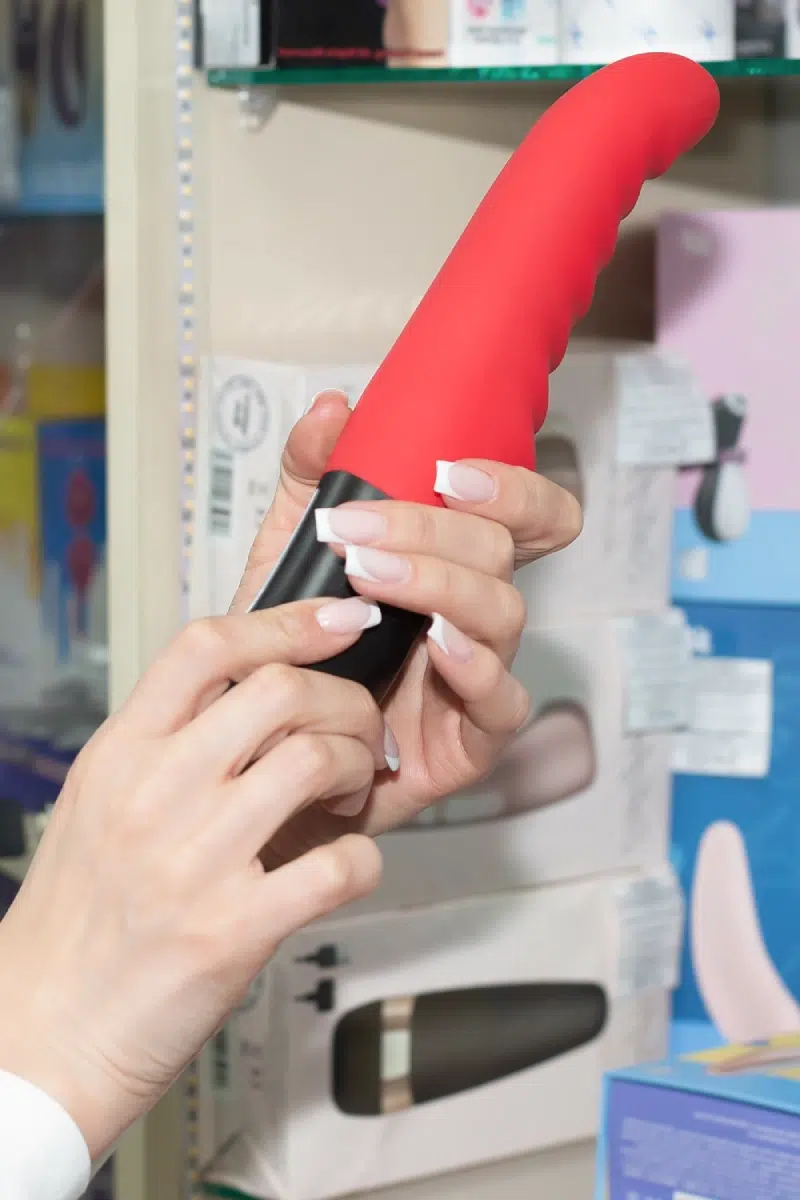 A person holding a red waterproof vibrator in a store, showcasing its design and quality.