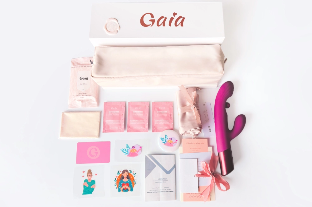 Gaia private label adult toy launch kit flat lay with branded gift box, storage pouch, rabbit vibrator, lube sachets, wipes, stickers, and insert cards.