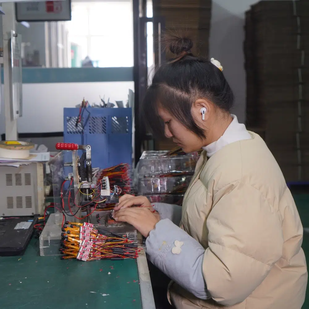Technician checking wired circuit boards and components at an electronics workbench.